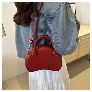 Detail view of red semi-circular leather handbag with silver hardware and adjustable strap