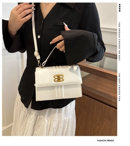 Détail d'un sac bandoulière blanc texturé avec boucle dorée porté par un mannequin