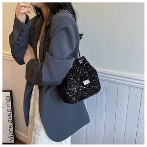 Fashionable black sequin bucket bag with silver chain strap worn with a gray blazer