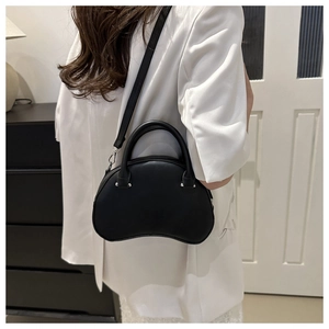 Detailed view of a black semi-circular crossbody bag worn by a model in a minimalist setting