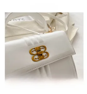 Gros plan détaillé d'un sac à main blanc en cuir avec un fermoir doré en forme de B