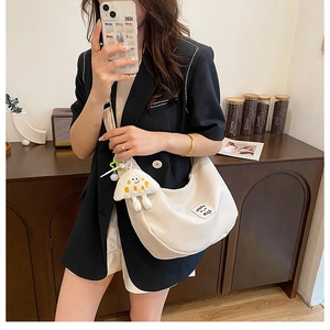 Détail du sac bandoulière blanc cassé en demi-lune avec breloque en peluche