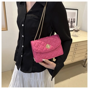 Macro view of magenta quilted leather bag with gold chain strap and turn-lock closure