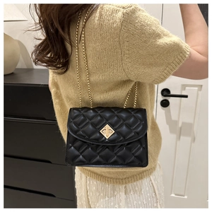 Detail of black quilted leather crossbody bag with gold chain and diamond clasp