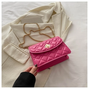 Detailed macro of rose pink quilted chain bag with gold geometric lock and leather strap
