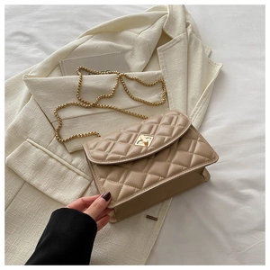 Detailed view of beige quilted crossbody bag with a gold metal twist lock and chain strap