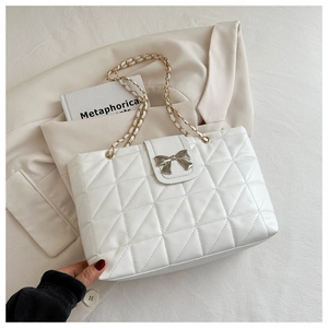 Close-up of quilted white tote bag featuring a silver bow buckle and metal chain strap
