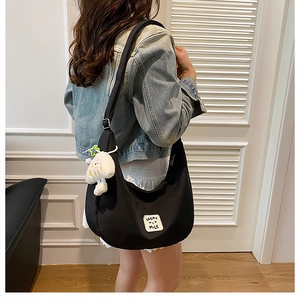 Détail du sac croissant en nylon noir avec écusson GREAT MILE et pendentif peluche