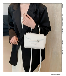 Detail of white lychee pattern leather handbag paired with a black blazer on a model