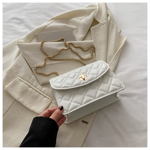 Close-up of white quilted leather bag with gold twist lock and elegant chain strap