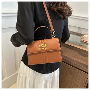 Sac bandoulière élégant en cuir marron avec boucle en métal doré dans un décor de vie
