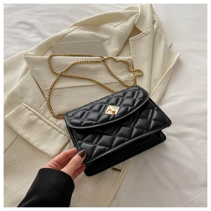 Detail of black quilted crossbody bag featuring golden chain strap and metal turn-lock closure