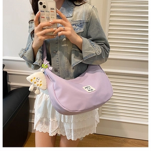 Détail du sac demi-lune en nylon violet clair avec patch SMILE et breloque champignon