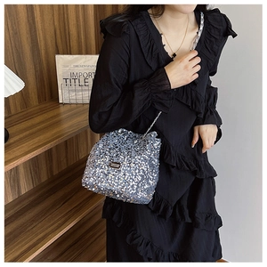 Detail of silver sequin bucket bag with metal chain strap and rectangle brand plate