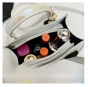 Internal capacity view of mini white quilted handbag holding lipsticks with shoulder strap