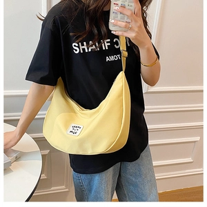 Détail d'un sac bandoulière demi-lune en nylon jaune vif avec sangle réglable et patch