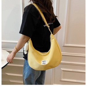 Détail du sac croissant en nylon jaune gingembre avec pendentif peluche et étiquette tissée