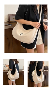 Détail du sac hobo blanc cassé avec écusson Great Mile et breloque poupée en peluche