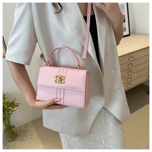 Sac à main rose en cuir avec fermoir doré et surpiqûres porté en bandoulière par le mannequin