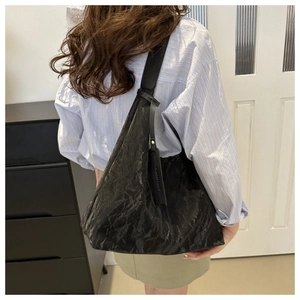 Détail du sac cabas plissé noir minimaliste porté à l'épaule par un mannequin chic