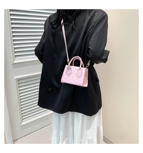 Detail of pink quilted crossbody bag with pearl luster finish on female model
