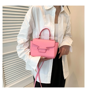 Close-up of pink mini crossbody bag with metal bar detail on a white shirt background