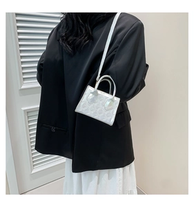 Mini borsa trapuntata argento abbinata a un blazer nero moderno e una gonna bianca
