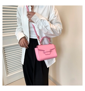 Detailed view of a pink mini crossbody bag with gold metal buckle on a model