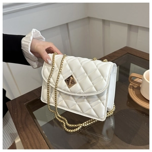 White quilted chain shoulder bag with gold twist lock shown in a lifestyle indoor setting