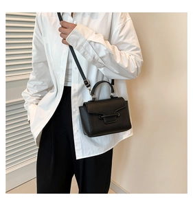 Lifestyle shot of a black litchi pattern flap bag with crossbody strap and top handle