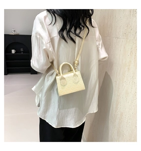 Detail of a beige quilted mini square bag with top handle and crossbody strap for women