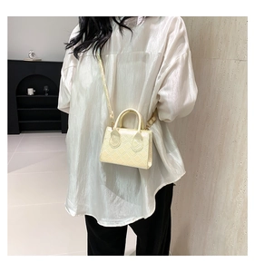 Dettaglio mini borsa quadrata trapuntata beige con finitura lucida e tracolla elegante