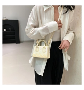 Dettaglio della borsa trapuntata beige con finitura perlata e tracolla regolabile