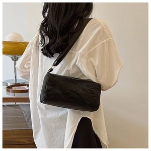 Minimalist black cylinder pillow bag with pleated texture and wide strap on model