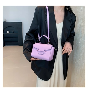 Close-up of lavender litchi leather crossbody bag with metallic bar buckle and shoulder strap