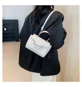 Close-up of white crossbody bag featuring premium lychee texture and metallic strap detail