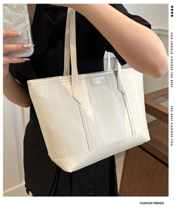 Dettaglio della trama a onde verticali e del logo metallico sulla borsa tote beige