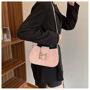 Borsa a tracolla rosa in vernice plissettata con fiocco d'argento indossata da modella