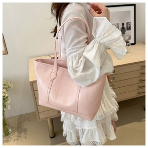 Dettaglio della borsa tote rosa goffrata coccodrillo su modella in ambiente elegante