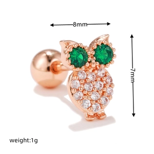 Macro shot of owl ear stud with green eyes and clear cubic zirconia in rose gold finish