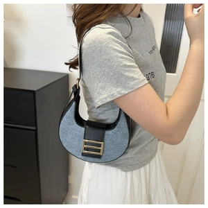 Close-up of crescent bag featuring blue denim patchwork and black leather details