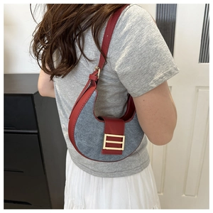 Detail of half-moon shoulder bag showing grey fabric texture and dark red leather trim