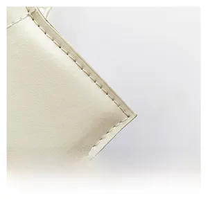 Close-up of premium white leather texture with precise stitching on a crossbody bag