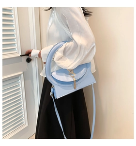 Close-up of light blue geometric handbag featuring gold S logo and round handle