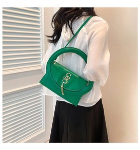 Detail of vibrant green leather handbag with unique circular handle and gold tassel fringe