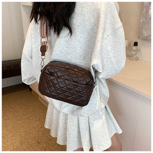 Detail einer dunkelbraunen Stepptasche mit gemustertem, breitem Web-Schultergurt