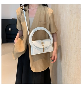 Detail of white leather handbag featuring a unique round handle and gold S-shaped metal buckle