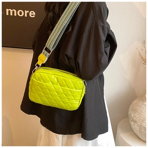 Detail einer neongelben Stepptasche mit breitem geometrischem Gurt und Silberbeschlägen