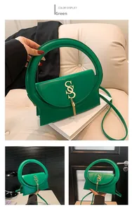 Détail du sac en cuir vert avec une poignée ronde unique et un pendentif doré en S