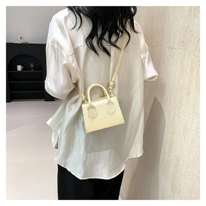 Minimalist beige quilted mini crossbody bag with top handle and sleek pearlescent finish